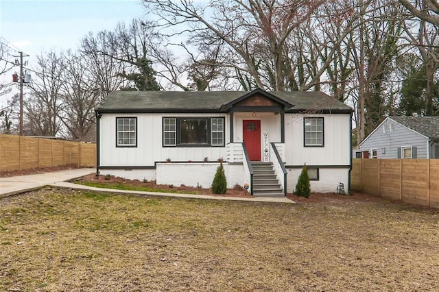 view of front facade featuring crawl space, a front lawn, board and batten siding, and fence private yard