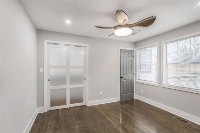 unfurnished bedroom with ceiling fan, dark wood finished floors, visible vents, and baseboards