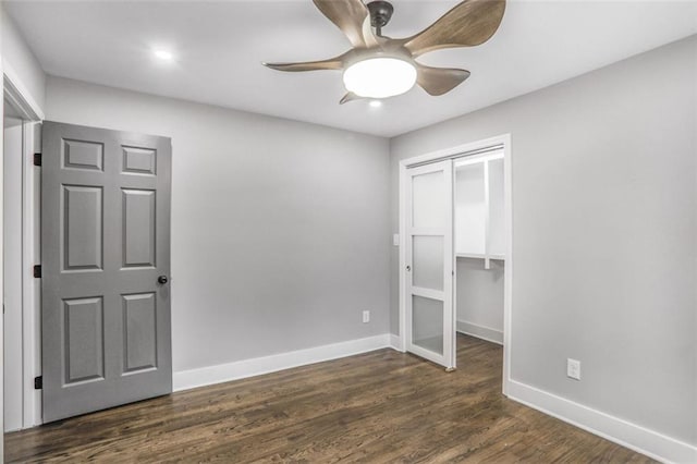 unfurnished bedroom with ceiling fan, a closet, baseboards, and dark wood-style flooring