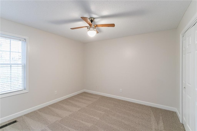 carpeted spare room featuring ceiling fan and a textured ceiling