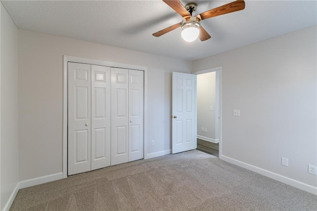 unfurnished bedroom with a textured ceiling, a closet, light colored carpet, and ceiling fan