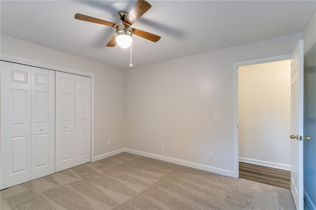 unfurnished bedroom with ceiling fan, a closet, light carpet, and a textured ceiling