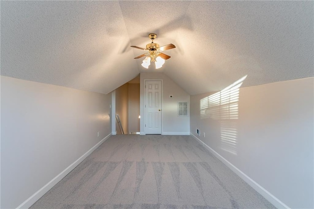 bonus room featuring a textured ceiling, light colored carpet, ceiling fan, and lofted ceiling