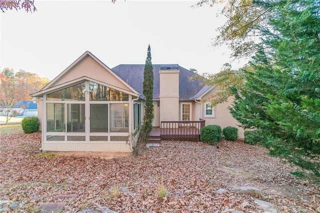 rear view of property featuring a wooden deck and a sunroom