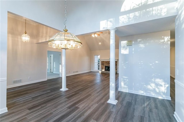 interior space with ornate columns, dark hardwood / wood-style flooring, high vaulted ceiling, a fireplace, and ceiling fan with notable chandelier