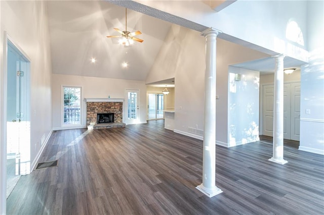 unfurnished living room featuring a stone fireplace, a wealth of natural light, high vaulted ceiling, and dark hardwood / wood-style floors