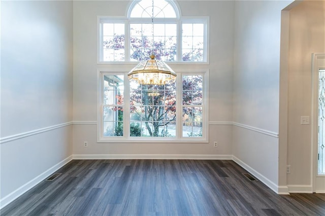 interior space with plenty of natural light, dark hardwood / wood-style flooring, and an inviting chandelier