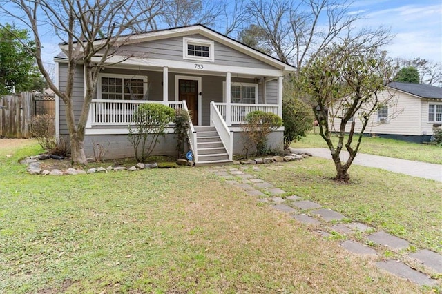 bungalow featuring a front yard, stairway, fence, and covered porch