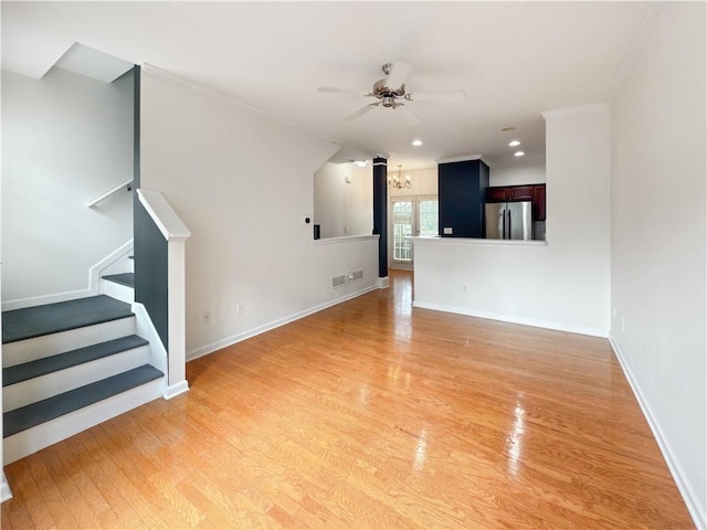 unfurnished living room with ceiling fan with notable chandelier and light wood-type flooring