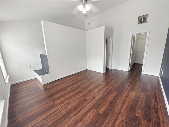 unfurnished bedroom featuring a closet, ceiling fan, vaulted ceiling, a walk in closet, and dark hardwood / wood-style flooring