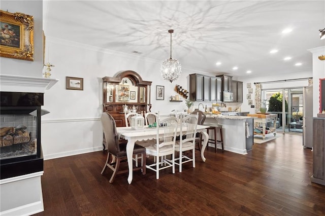 dining room featuring a fireplace, ornamental molding, dark wood-type flooring, and recessed lighting