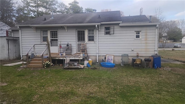 rear view of property featuring roof with shingles, a yard, an outdoor structure, and a storage unit