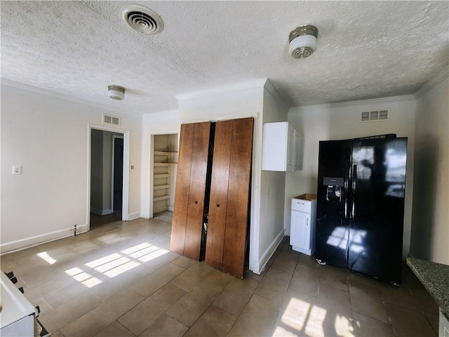 kitchen featuring white cabinetry, visible vents, black fridge, and ornamental molding