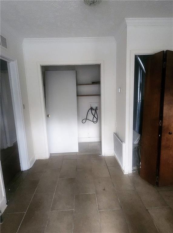 hallway featuring a textured ceiling, visible vents, and crown molding