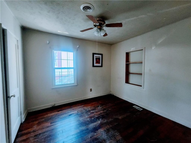 empty room featuring a ceiling fan, visible vents, a textured ceiling, and wood finished floors