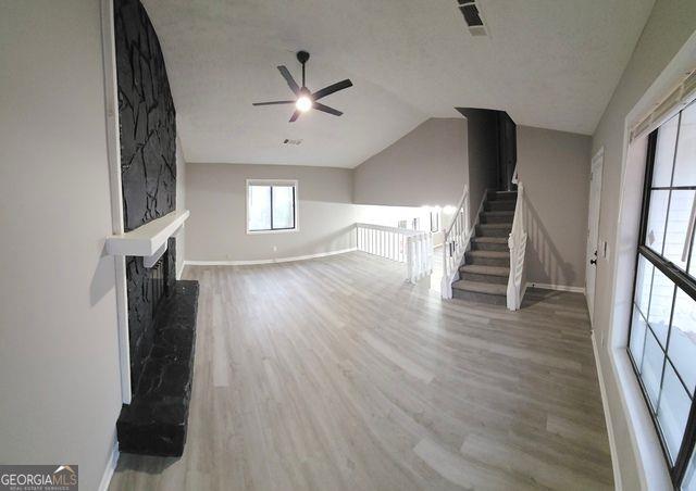 unfurnished living room with ceiling fan, wood-type flooring, and lofted ceiling