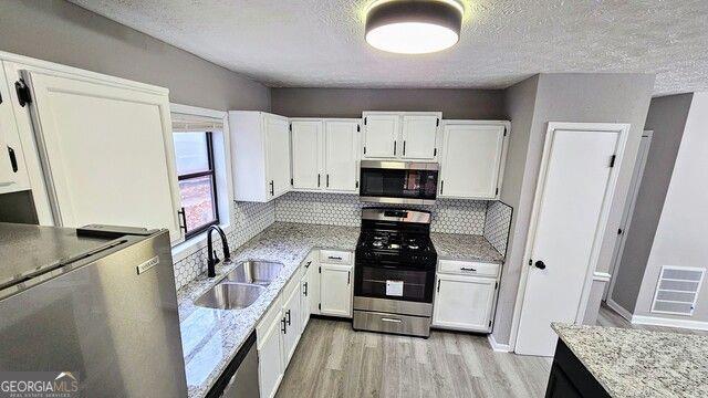 kitchen with white cabinets, decorative backsplash, appliances with stainless steel finishes, and sink