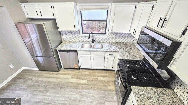 kitchen featuring backsplash, sink, light stone countertops, appliances with stainless steel finishes, and white cabinets