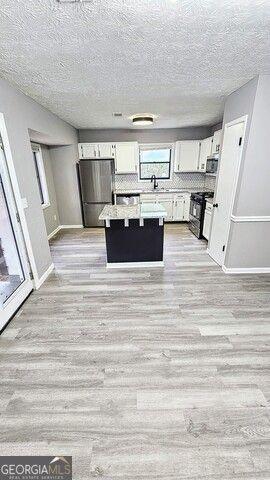 kitchen featuring stainless steel appliances, light hardwood / wood-style flooring, white cabinets, and a center island