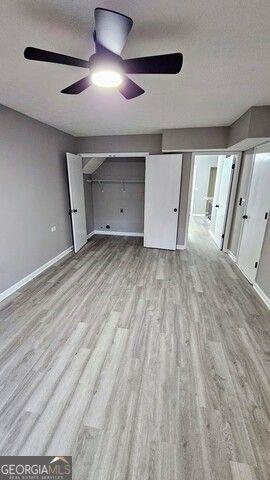 unfurnished bedroom featuring ceiling fan, a textured ceiling, and light hardwood / wood-style flooring