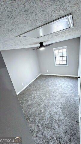 spare room featuring ceiling fan, a textured ceiling, and carpet flooring