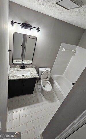 bathroom with toilet, a textured ceiling, a bath, and vanity