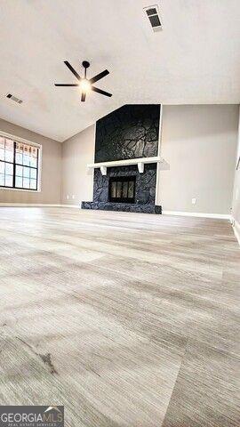 unfurnished living room featuring ceiling fan, carpet floors, and a stone fireplace