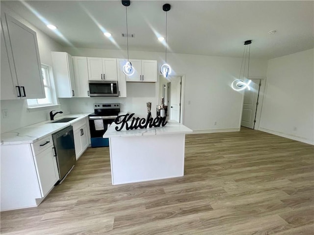 kitchen with a sink, light wood finished floors, appliances with stainless steel finishes, a center island, and decorative light fixtures