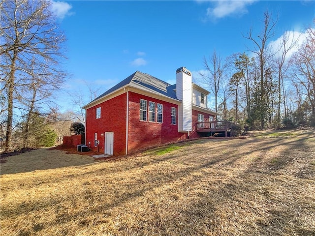 view of side of property featuring central AC, a deck, and a lawn