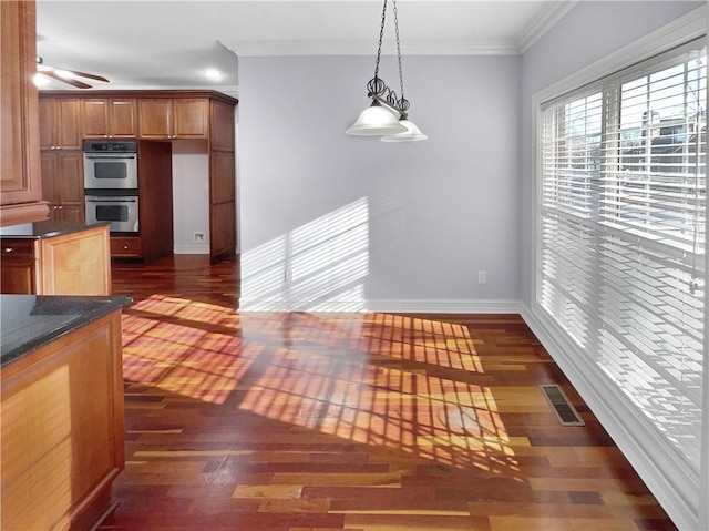 kitchen featuring dark wood-type flooring, decorative light fixtures, double oven, and ornamental molding