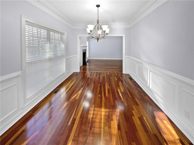 unfurnished dining area with dark hardwood / wood-style flooring, an inviting chandelier, and crown molding