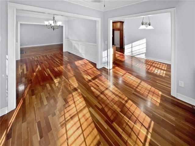 spare room with wood-type flooring, an inviting chandelier, and crown molding