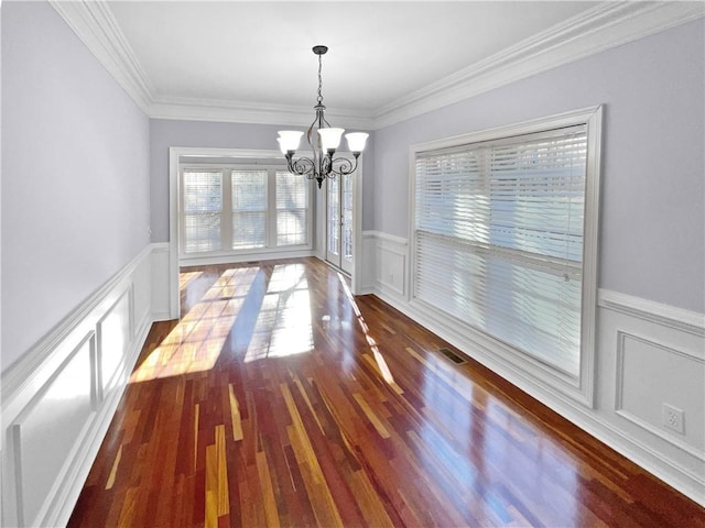 unfurnished dining area featuring hardwood / wood-style flooring, a chandelier, and ornamental molding