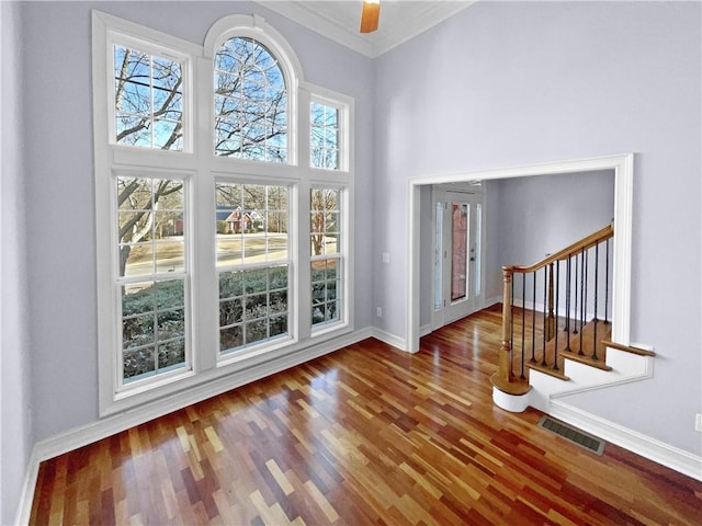 entrance foyer featuring a high ceiling, ornamental molding, ceiling fan, and dark wood-type flooring