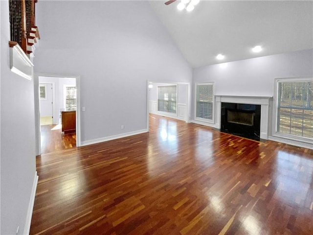 unfurnished living room with dark hardwood / wood-style floors, ceiling fan, a premium fireplace, and high vaulted ceiling