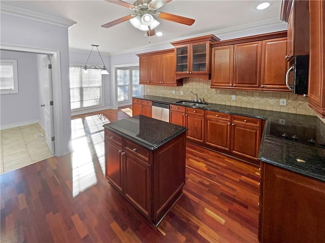 kitchen with sink, stainless steel appliances, dark stone countertops, a kitchen island, and ornamental molding