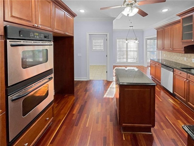 kitchen with a center island, ceiling fan with notable chandelier, crown molding, appliances with stainless steel finishes, and tasteful backsplash