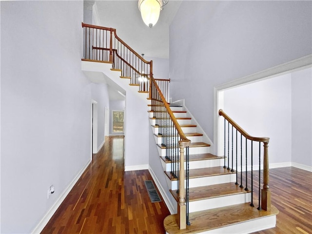 stairs with a high ceiling and wood-type flooring