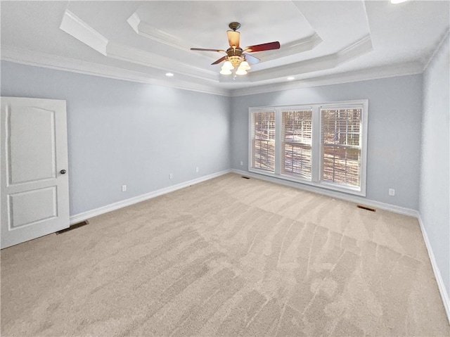 carpeted empty room with a tray ceiling, ceiling fan, and crown molding