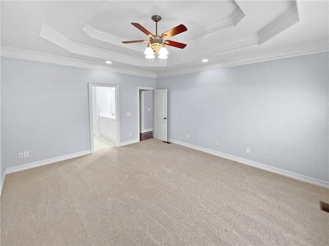 spare room with a tray ceiling, ceiling fan, crown molding, and light colored carpet