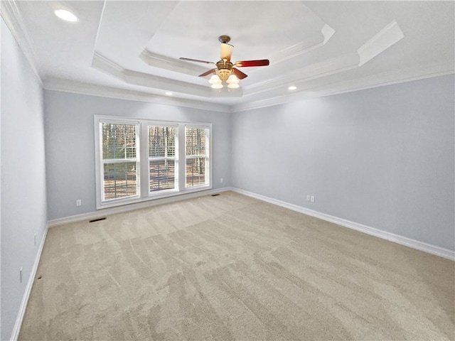 carpeted empty room featuring ceiling fan, a raised ceiling, and ornamental molding