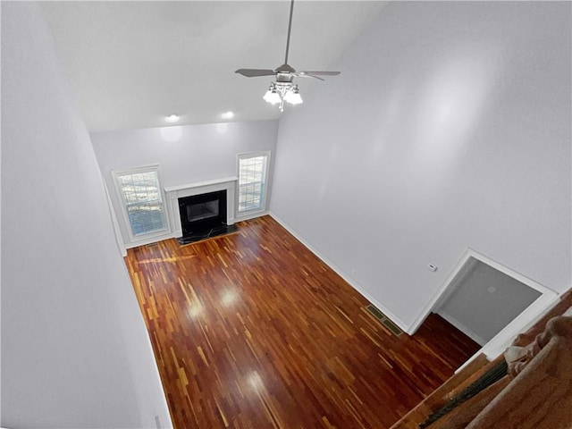 unfurnished living room with vaulted ceiling, ceiling fan, a fireplace, and dark hardwood / wood-style floors