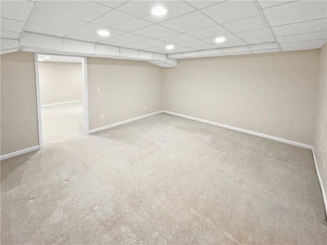 basement featuring a drop ceiling and light colored carpet