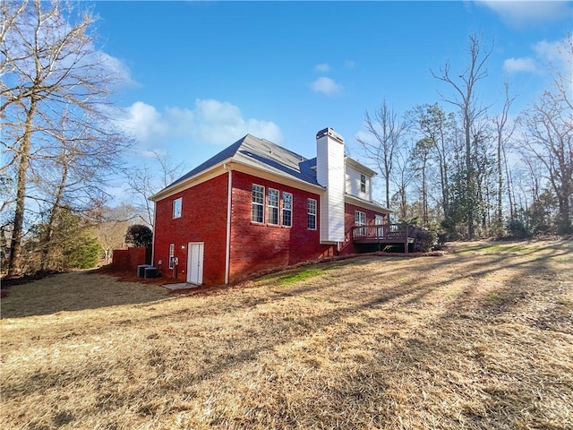 view of property exterior with a deck, a yard, and central AC