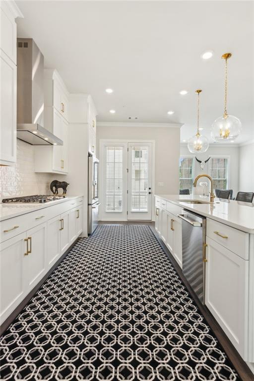 427 Burton Dr, Alpharetta, GA 30009 - kitchen featuring wall chimney exhaust hood, stainless steel appliances, a sink, crown molding, and white cabinetry