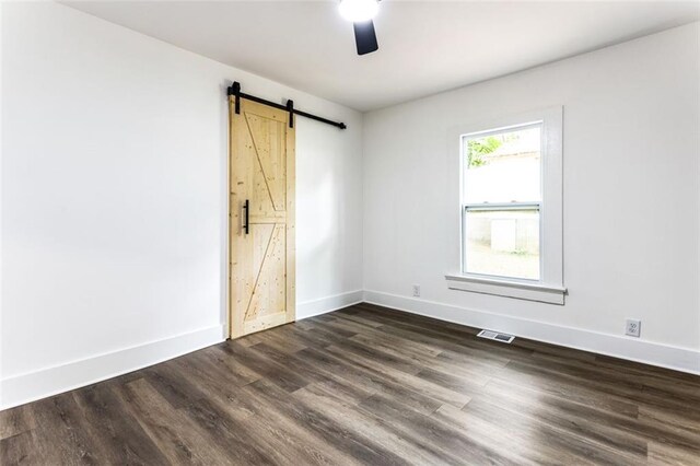 interior space with ceiling fan, a barn door, and dark hardwood / wood-style flooring