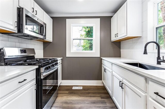 kitchen featuring sink, white cabinets, backsplash, appliances with stainless steel finishes, and dark hardwood / wood-style flooring