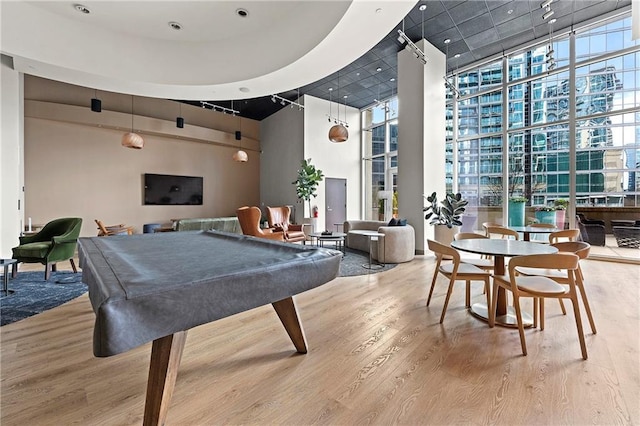 rec room with a towering ceiling, wood-type flooring, billiards, and floor to ceiling windows