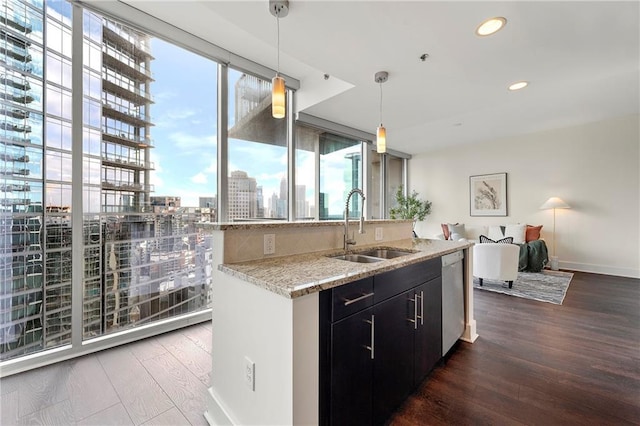 kitchen featuring sink, stainless steel dishwasher, dark hardwood / wood-style flooring, pendant lighting, and light stone countertops