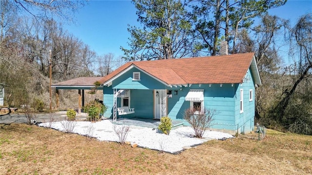 bungalow featuring driveway, a chimney, and a front yard